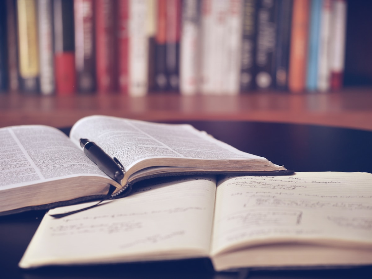 Open book and notebook with a pen on a dark desk for quiet reflection